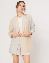 Blazer oversized de corte recto en lino, color beige y gris. Largo a la cadera, con hombreras finitas forradas, costuras internas con sesgo combinado y bolsillos delanteros.