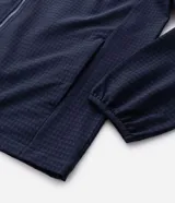 Chaqueta deportiva masculina de color azul marino, confeccionada en tejido técnico repelente al agua con acabado texturizado. Presenta cierre frontal con cremallera, capucha integrada y estampado de coordenadas en el pecho.