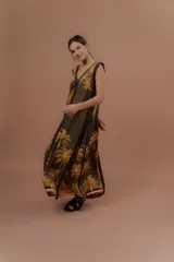 Vestido largo verde militar con estampa tropical de palmeras en tonos amarillos, escote en V y detalles en marrón.