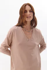 Buzo color beige de tejido suave, con escote en V y mangas largas.