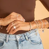 Brazalete tipo esclava de alambre redondo en plata 925, con dije de medalla circular colgante.