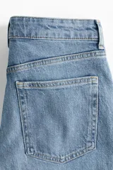 Jean de tiro alto con corte wide leg y piernas amplias. Confeccionado en denim de algodón con leve stretch, presenta diseño de cinco bolsillos, cierre con botón y bajo con detalle de ruedo desgastado.