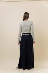 Pantalón wide leg de tiro alto en color negro, con diseño de pinzas delanteras que aportan volumen y caída fluida. Incluye bolsillos laterales y un lazo desmontable en la cintura que combina cordón con cinta de estampado animal print.