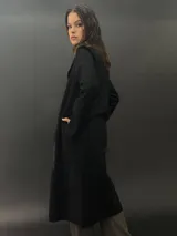 Tapado largo de paño de lana color negro con estampado abstracto brillante en el frente. Tiene cuello con solapas, bolsillos laterales y terminación al tallo vivo.