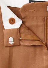 Pantalón de vestir de corte recto y tiro medio, color marrón, con pinzas frontales y bolsillos laterales.