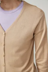 Cárdigan color beige con escote en V y cierre frontal con botones.