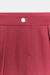 Pantalón de tiro bajo color fucsia, con pliegues delanteros, bolsillos frontales, pernera holgada y cierre frontal con cremallera y botón.