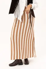 Falda larga tejida a rayas verticales color beige y blanco, con pretina elástica y tajos laterales.