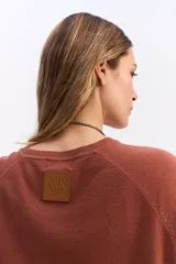 Sweater de punto negro con cuello redondo, manga larga y calce relajado. Presenta una costura vertical central en el frente y puños acanalados.