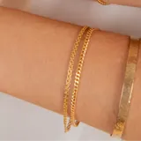 Set de pulseras de oro 18k que incluye dos brazaletes rígidos con texturas diferentes y dos pulseras de cadena fina.