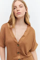 Remera marrón de tejido liso, con escote en V, mangas cortas y cierre frontal con botones.