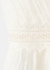 Top blanco sin mangas, con escote en V pronunciado, detalles de encaje y lazos ajustables en el frente. Presenta diseño corto y ligero con dobladillo con vuelo.