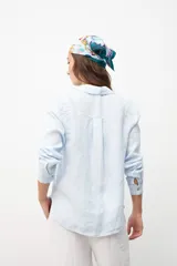 Camisa de lino en color celeste, con cuello clásico, cierre frontal de botones y bolsillo en el pecho.