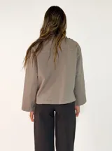 Chaqueta negra de algodón con diseño de volados en el frente, cierre de botones y bolsillos laterales.