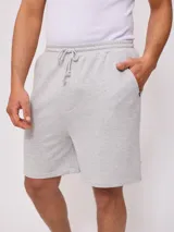 Bermuda deportiva gris confeccionada en 60% algodón y 40% poliéster, con cintura elástica ajustable con cordón.