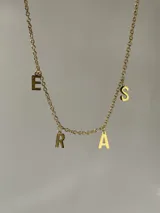 Collar dorado con cadena de eslabones y colgantes con las letras 'E', 'R', 'A' y 'S'.