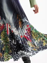 Pollera midi plisada con estampa digital artística y detalles de círculos calados. Presenta una cintura con elástico negro a la vista.