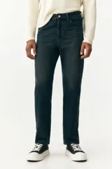 Jean de cinco bolsillos en denim de algodón rígido, color azul oscuro lavado. Modelo de cintura clásica con cierre de botón y corte relajado de cadera a bajo con pierna recta más amplia a partir del muslo.