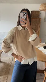 Sweater de punto color beige, con cuello redondo y mangas largas abullonadas. Presenta detalles bordados con lentejuelas y perlas en los hombros y parte superior de las mangas.