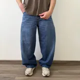 Pantalón jean de corte barrel, color azul clásico con efecto desgastado y diseño amplio y curvado en las piernas.