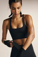 Bralette deportivo negro con escote cuadrado y espalda en V, confeccionado en tejido suave y transpirable. Presenta tirantes finos y banda inferior de soporte.