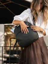 Mochila versátil convertible en cartera, color beige con detalles en marrón. Cuenta con doble asa superior, correas ajustables y desmontables, bolsillo frontal con cierre y compartimento principal amplio.