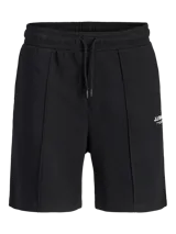 Bermuda deportiva negra de calce relajado, con cintura elástica ajustable mediante cordón, bolsillos laterales y costuras frontales en relieve. Presenta un pequeño estampado de texto en la pierna izquierda.