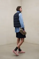 Chaleco acolchado blanco sin mangas, con diseño de franjas horizontales, cuello alto y cierre frontal con botones a presión. Modelo Olimpo de Ecoalf.