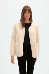 Chaqueta de pana color natural, con cuello a la base, cierre frontal y bolsillos delanteros tipo parche. Diseño holgado de manga larga.