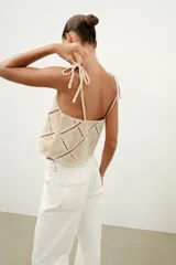 Top de escote recto color beige con tirantes finos ajustables con lazadas. Presenta un diseño con apliques de tejido tipo crochet en patrón geométrico de rombos.