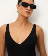 Blusa sin mangas de punto acanalado color crema, con escote en V y espalda descubierta. Confeccionada en una mezcla de viscosa y poliamida, presenta un ajuste al cuerpo y textura vertical en relieve.