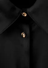 Camisa de poliéster con acabado satinado, color negro, de manga larga con puños abotonados, diseño recto, cuello camisero y cierre delantero con botones.