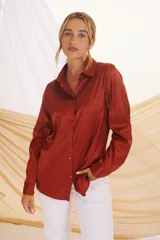 Camisa beige con estampado de líneas diagonales, cuello clásico, cierre con botones y mangas largas con puños abotonados.