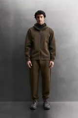 Pantalón jogger de entrenamiento regular fit confeccionado en tejido técnico compacto de algodón con elasticidad y efecto neopreno. Cuenta con cintura elástica ajustable con cordón, bolsillos frontales, un bolsillo lateral con cierre de cremallera y bajo acabado en puño.