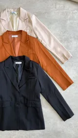 Blazer verde esmeralda de corte clásico con solapas y cierre con botones.