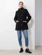 Gabardina impermeable negra, con capucha desmontable, cierre central oculto con botones a presión, bolsillos delanteros y cintura ajustable con jareta interna. Incluye forro interno desmontable.