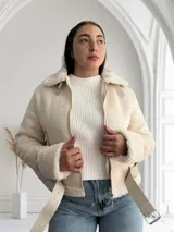 Chaqueta color crema con cuello y puños de piel sintética, cierre frontal con cremallera y cinturón ajustable en la cintura.
