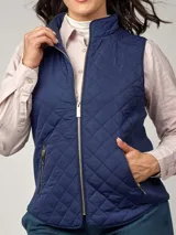 Chaleco sin mangas capitoneado en color beige, con cierre frontal y bolsillos laterales. Presenta un diseño entallado con cuello alto.