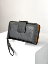 Billetera grande de cuero negro con textura de reptil y detalles de costuras en contraste. Cuenta con solapa frontal con cierre magnético y correa de muñeca extraíble.