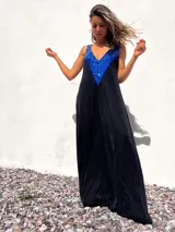 Vestido largo de corte holgado en color negro, con escote en V profundo decorado con lentejuelas azules brillantes. Presenta breteles anchos y una caída fluida.