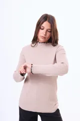 Buzo de tejido de punto acanalado en color beige, con cuello alto y terminaciones con borde ondulado en contraste negro en cuello y puños.