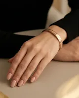 Esclava rígida de acero con baño de oro rosa y diseño de guarda griega grabada en toda su superficie.