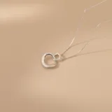 Conjunto de collar y dije en plata 925, compuesto por una cadena fina y un dije circular con diseño orgánico entrelazado.