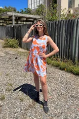 Vestido corto sin mangas con estampado abstracto en tonos naranja y celeste.