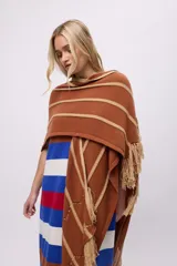 Ruana tejida de punto color terracota con franjas horizontales y diagonales en color beige. Presenta flecos largos en los bordes.