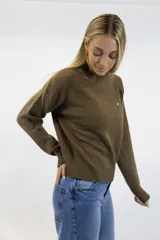 Buzo de tejido fino color beige con delicados destellos brillantes integrados en la trama. Presenta cuello redondo, mangas largas con corte raglán y terminaciones acanaladas en cuello, puños y cintura.