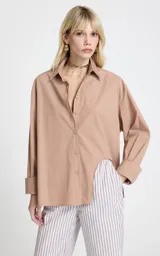 Camisa de corte recto y diseño oversize, con estampado de rayas verticales en tonos marrón y blanco. Presenta cuello clásico estructurado, mangas largas con puños anchos, hombros caídos y bajo asimétrico con abertura lateral. Cierre frontal mediante botones.
