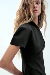 Vestido corto negro con escote en V, mangas cortas con volumen y cierre frontal con cremallera.