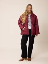 Campera acolchada de diseño matelassé con patrón de rombos, color bordó. Presenta cuello camisero, cierre frontal con cremallera metálica, cintura entallada con elástico y bolsillos laterales. Incluye un pequeño bordado distintivo en el pecho.