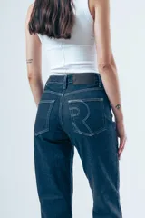 Jean de tiro medio con silueta recta que se amplía levemente hacia la botamanga, generando un efecto flare. Confeccionado en denim de estructura firme, cuenta con diseño de cinco bolsillos, cierre frontal y presillas en la cintura.
